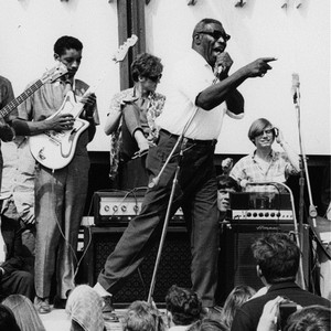 Howlin' Wolf pointing into a crowd while performing on an outdoor stage.