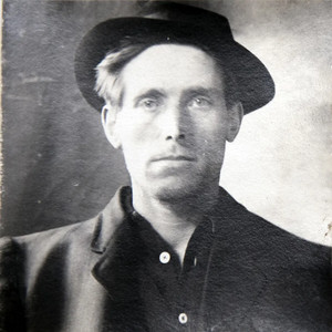 Studio portrait of Dock Boggs in a dark hat staring directly at the camera.